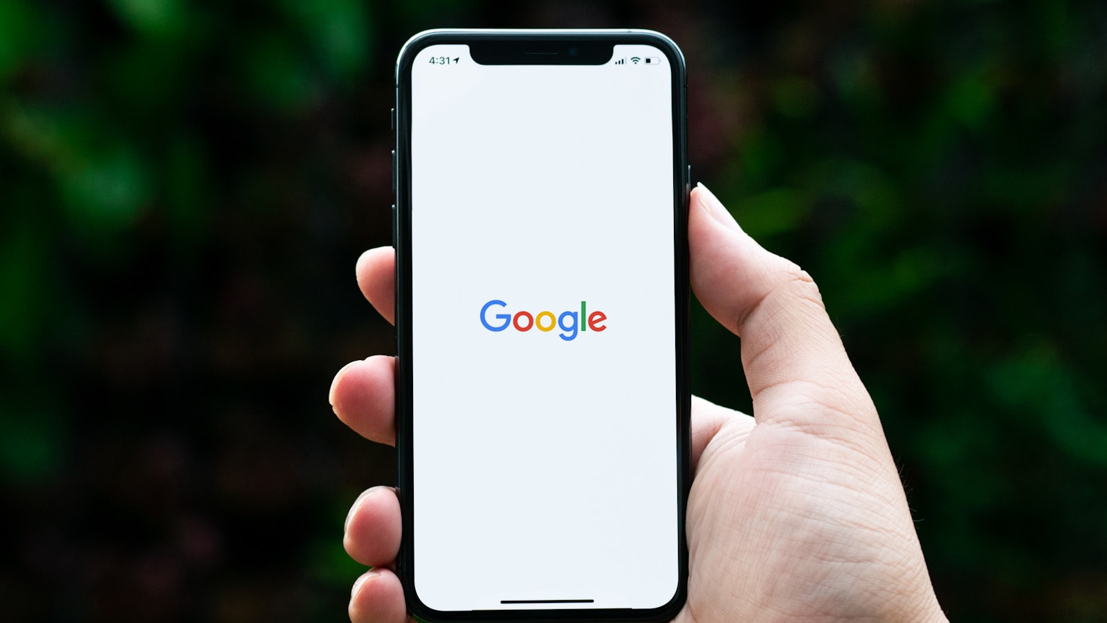 Main tenant un smartphone affichant le logo Google